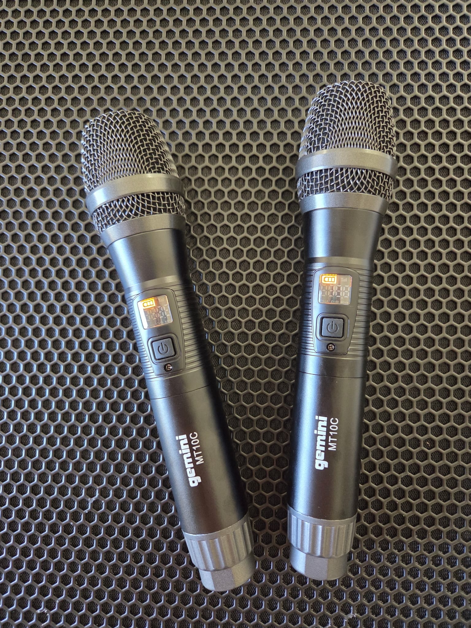 Two Gemini MT10C handheld wireless microphones resting on a speaker grille