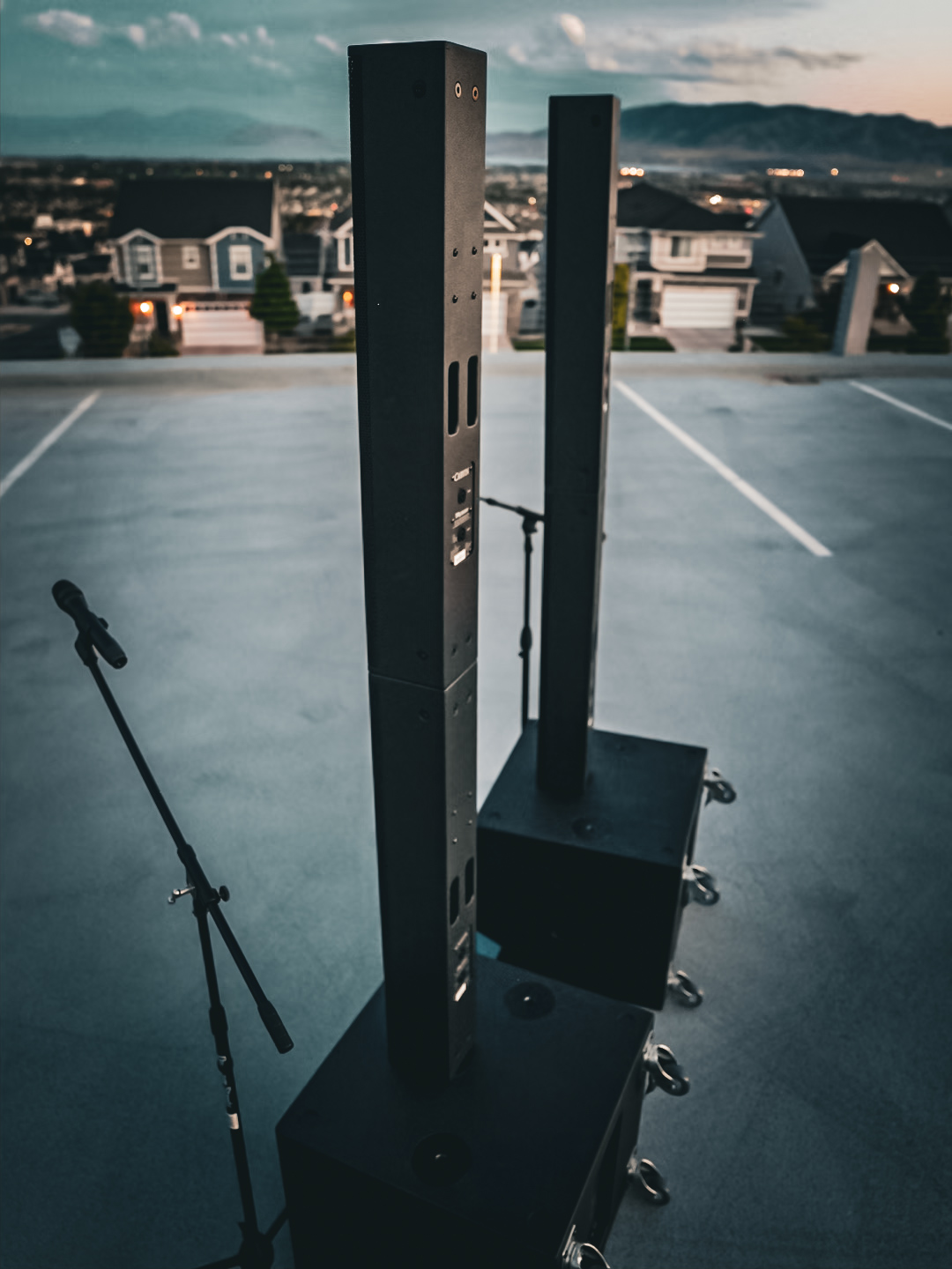 Column array speakers and a subwoofer set up on a rooftop deck at dusk above a Utah valley