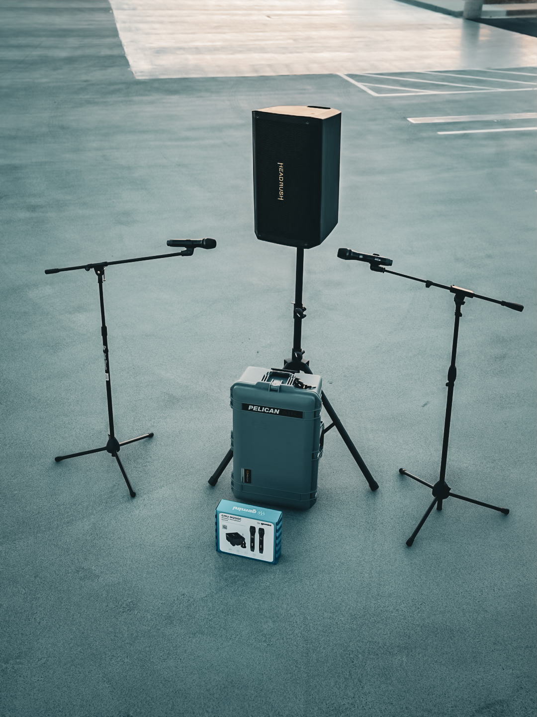 Two microphone stands positioned either side of a powered speaker on a stand