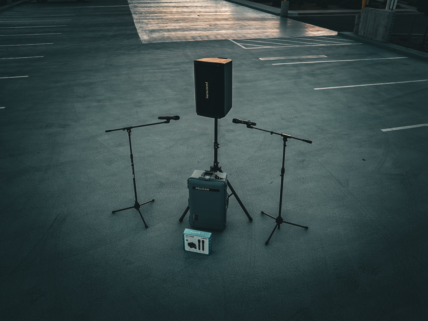 A portable PA system and microphone stands ready inside a covered parking structure