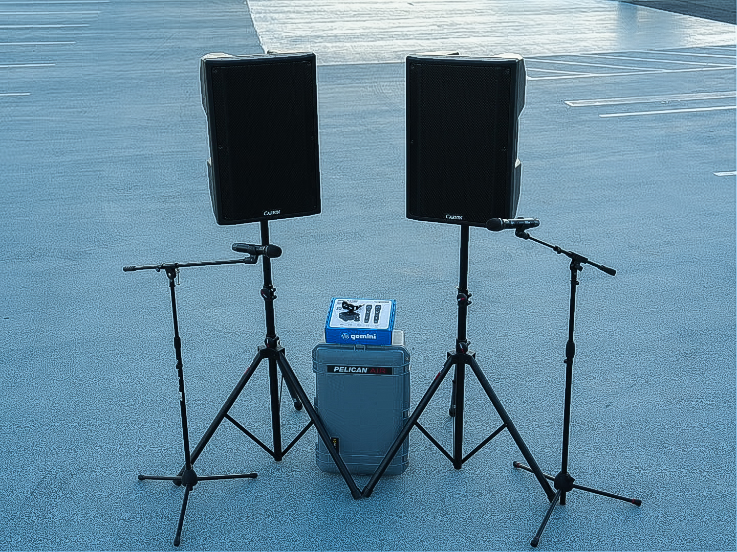Two Carvin powered speakers on stands with a mixer case between them