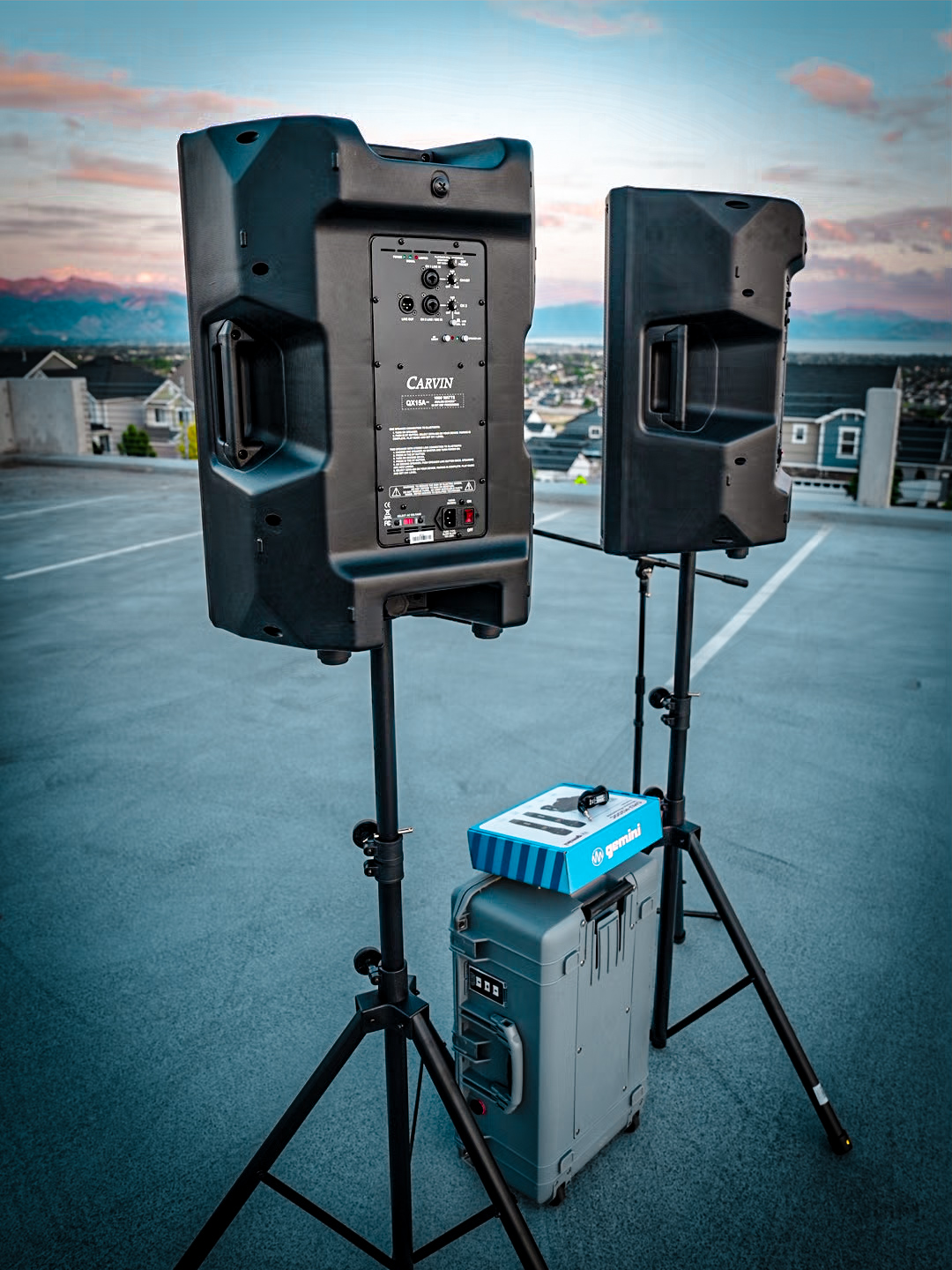 Rear view of two Carvin powered speakers on stands at sunset