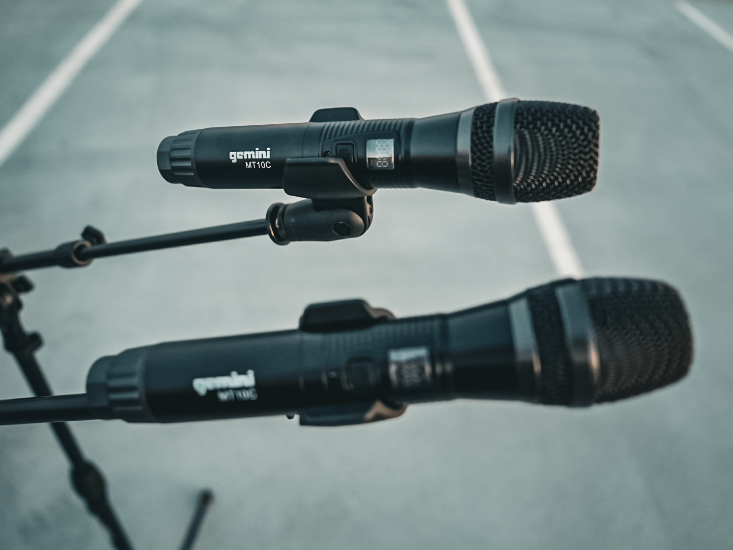 Two Gemini MT10C wireless handheld microphones clipped into boom stands
