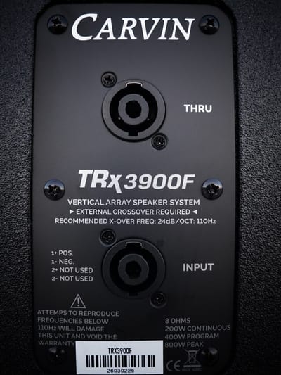 The connector plate of a Carvin TRx3900F array speaker, its speakON input and through sockets labelled either side of the cabinet specifications