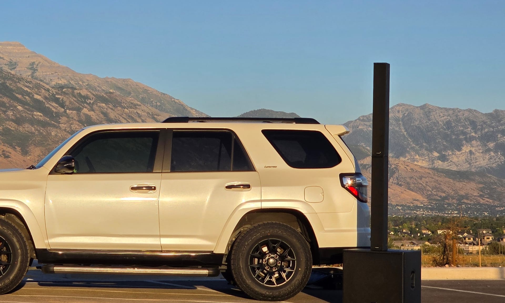 A column array standing on its powered subwoofer beside the branded Sound Systems SUV, the Wasatch range behind it at golden hour
